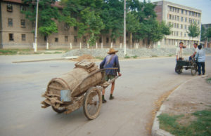 A man hauls a two-wheeled cart of night soil from city latrines to the farm field south of campus.